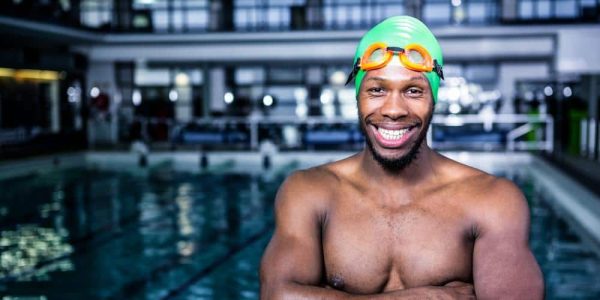 Fit swimmer standing with arms crossed in swimming pool